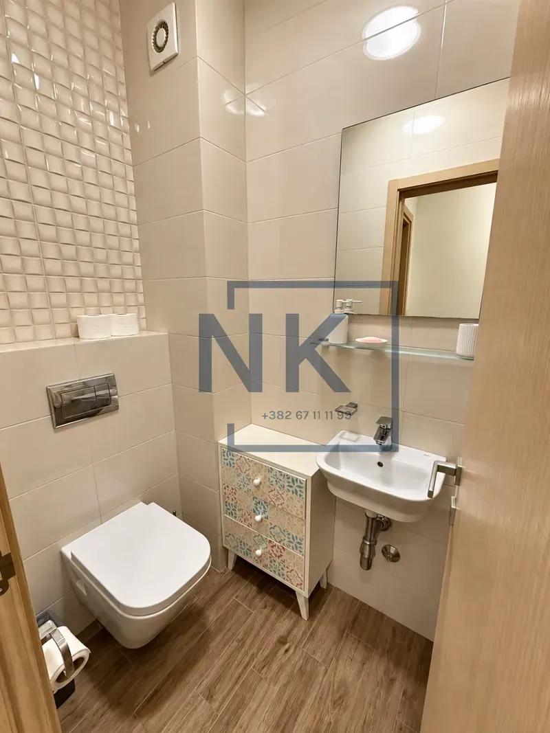 Manje kupatilo sa WC šoljom, umivaonikom i ogledalom.