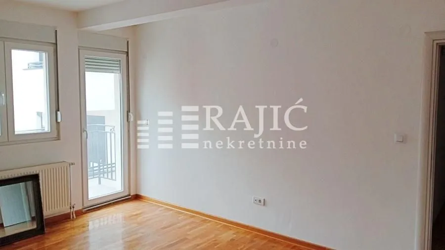 Empty room with parquet flooring and balcony access.