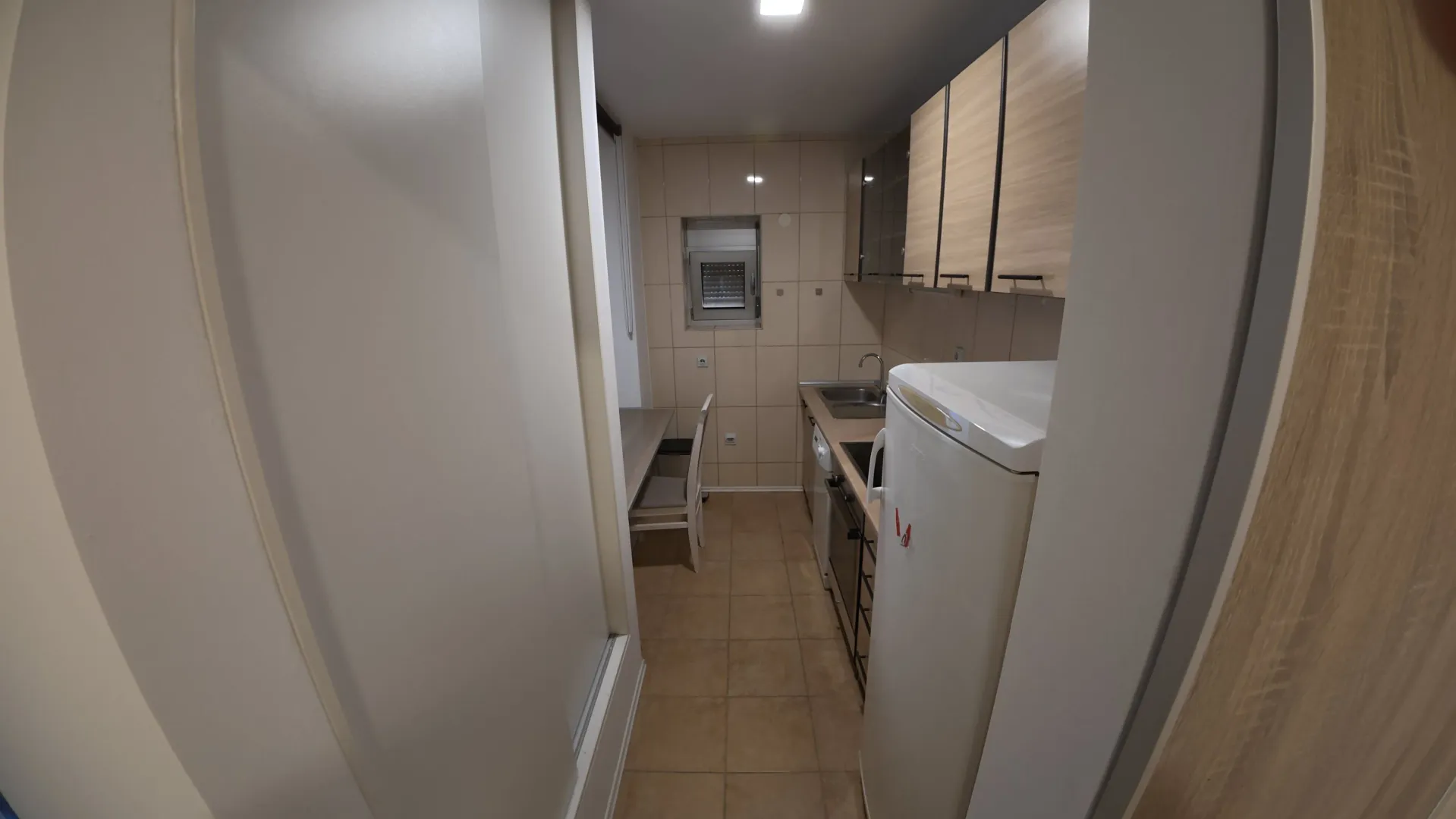 Smaller equipped kitchen with white goods and a dining table.