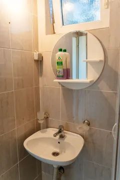 A simple sink with a mirror in a bathroom with light tiles. - image 5
