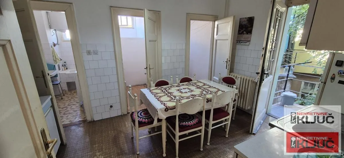 Trpezarija sa stolom i stolicama, sa izlazom na terasu i pogledom na druge prostorije.