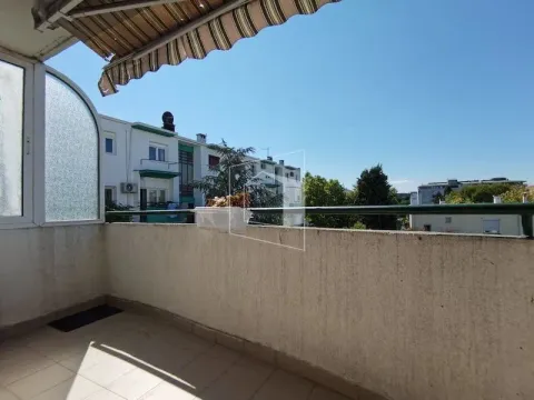 Natkriveni balkon sa pogledom na okolne zgrade i zelenilo. - image 6