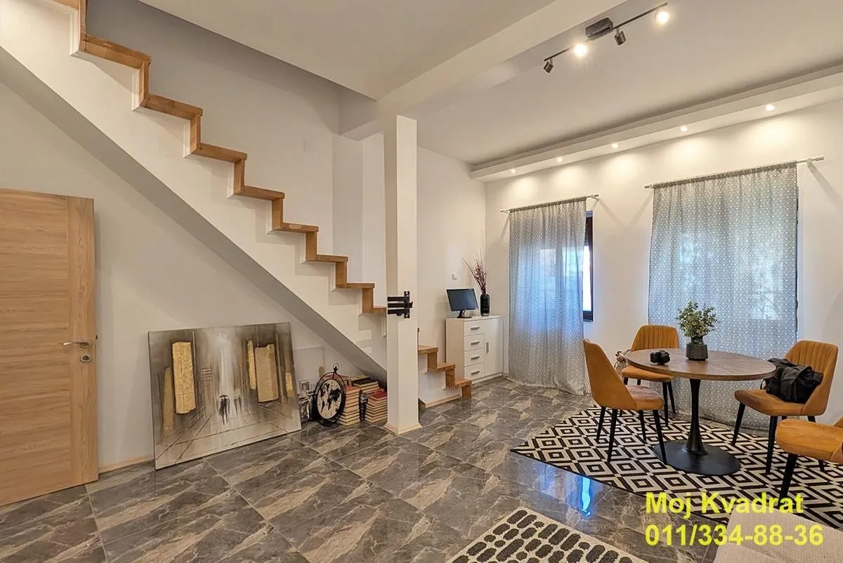 Living room with a dining table, internal stairs, and marble floor.