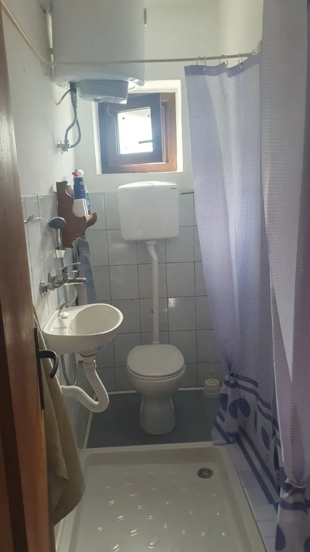 Manje kupatilo sa tuš kabinom, umivaonikom i toaletom.