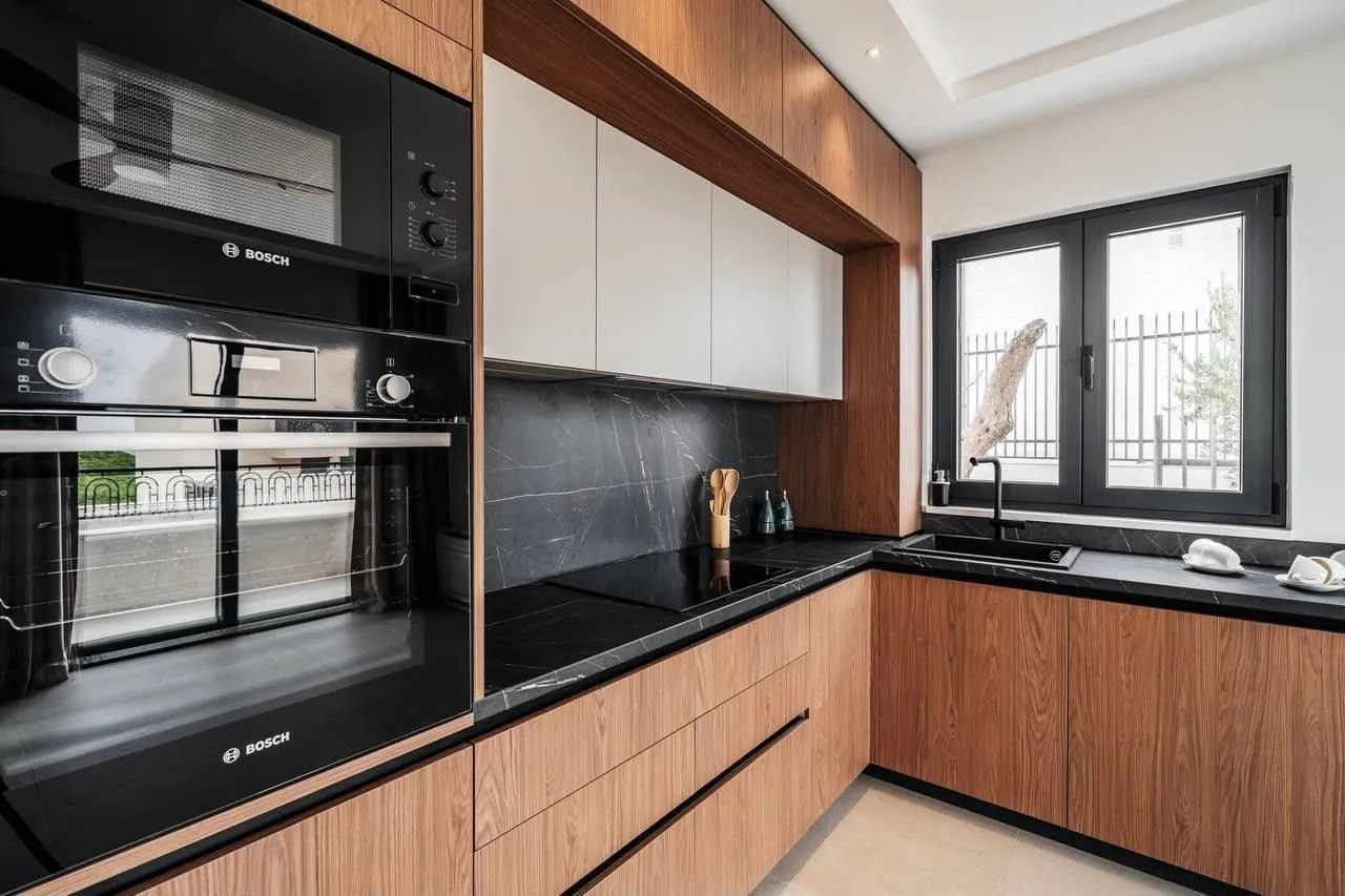 Modern kitchen with wooden cabinetry, black countertop, and built-in oven.