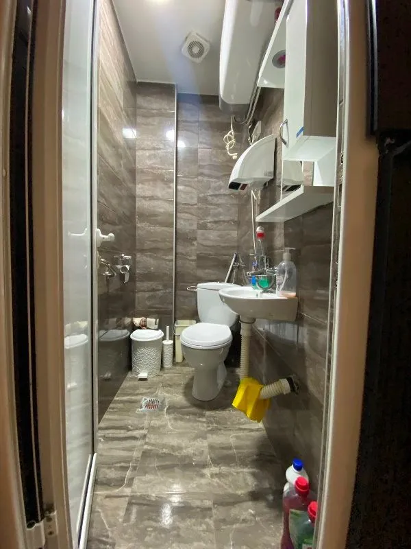 View of a small tiled bathroom with a shower cabin and toilet fixtures.