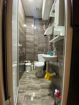 View of a small tiled bathroom with a shower cabin and toilet fixtures. - image 13