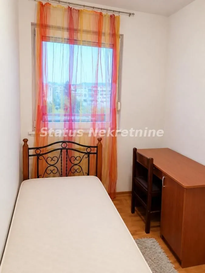 Small bedroom with a bed and a desk by the window.