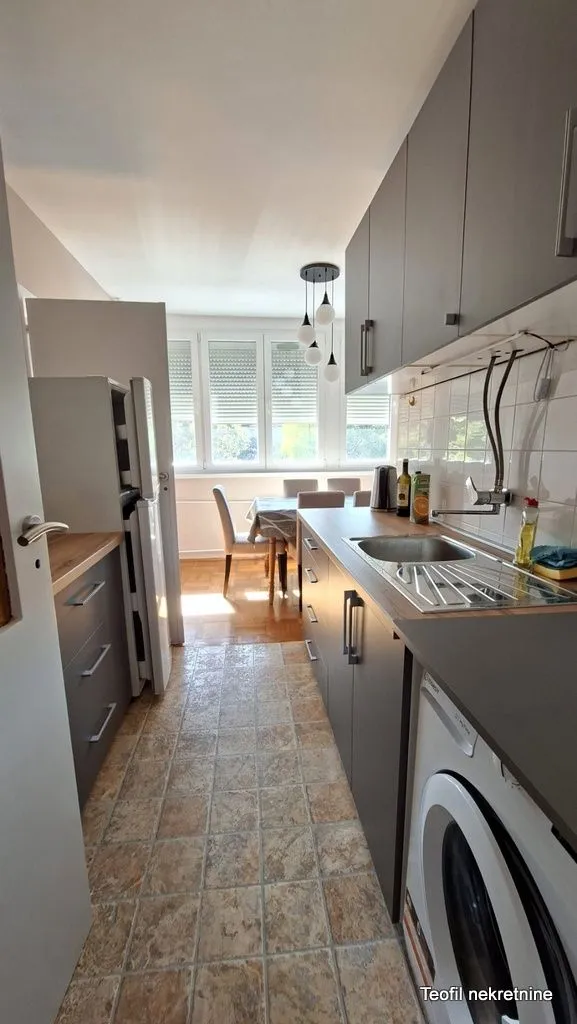 Small kitchen with dark cabinetry and a dining area in the background.