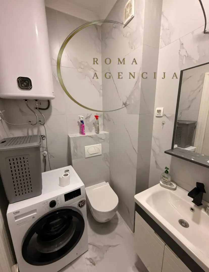Moderno opremljeno kupatilo sa tuš kabinom, umivaonikom i veš mašinom.