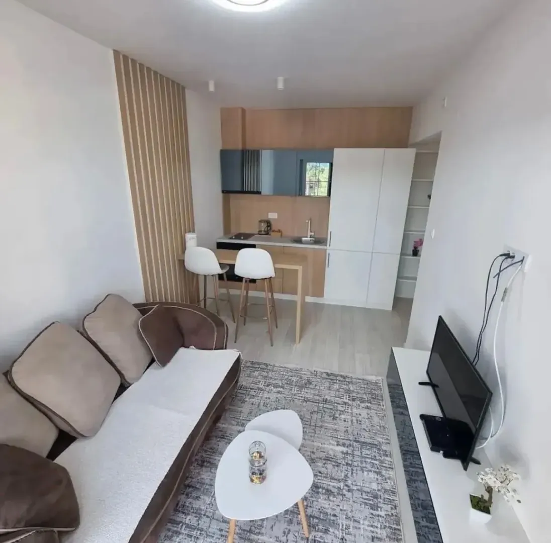 Living room with a sofa and dining area connected to the kitchen.