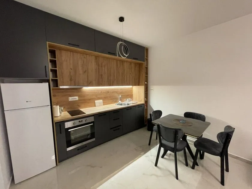 Modern kitchen with dark cabinetry and a dining table.