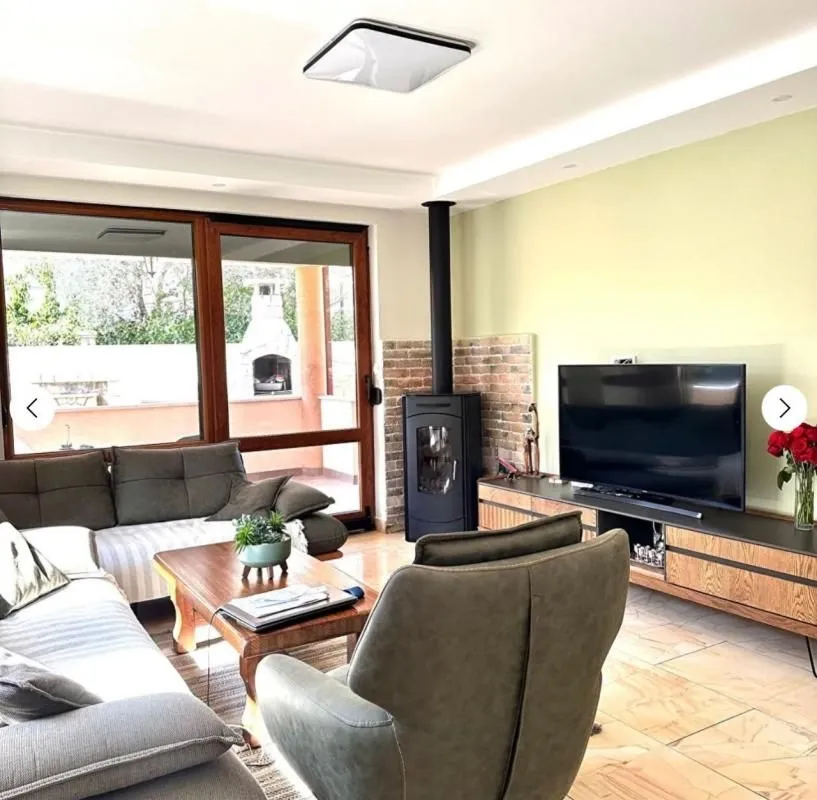 Living room with a sofa set, wood-burning stove, and a view of the terrace.
