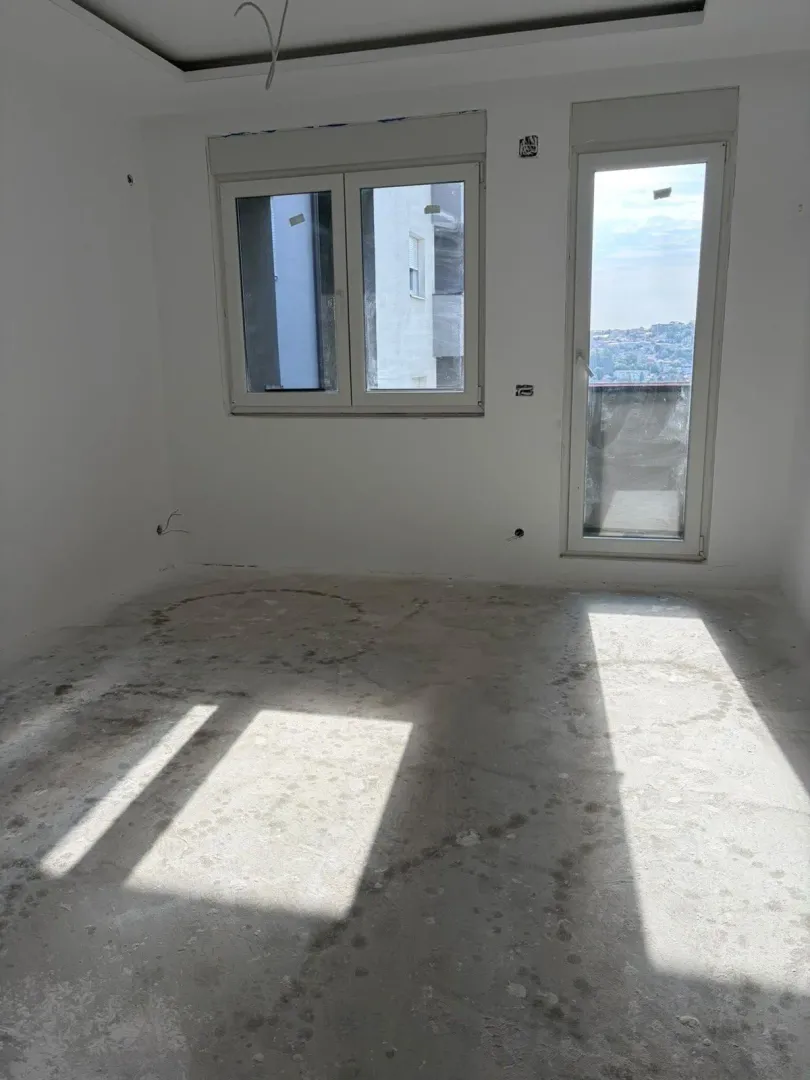 Prazna prostorija u izgradnji sa prozorom i balkonskim vratima.