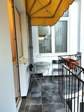 Small balcony with a table, chairs, and an awning. - image 11