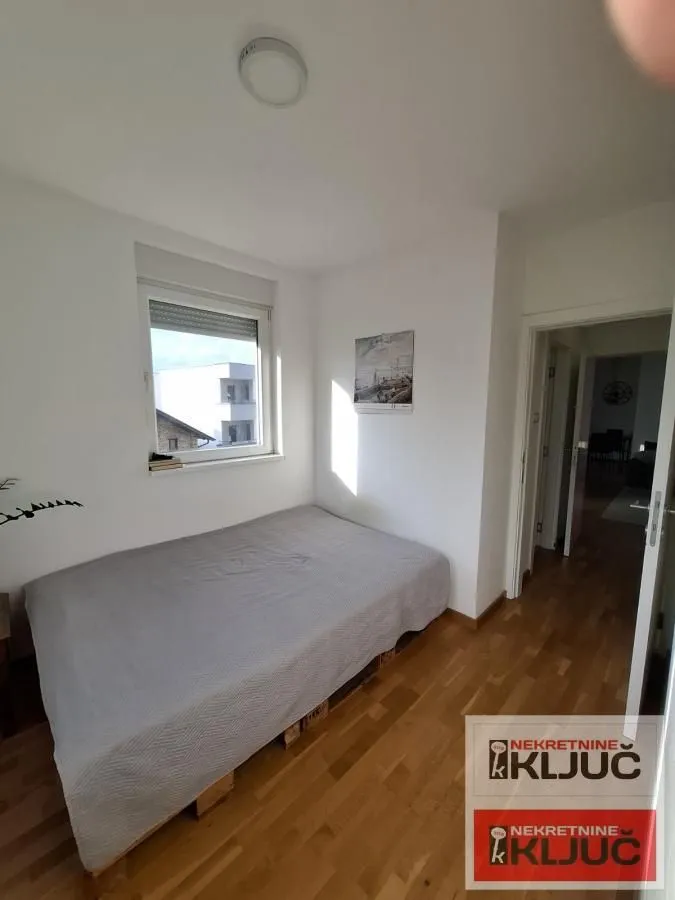 Manja spavaća soba sa bračnim krevetom i prozorom.