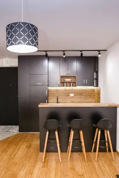 Modern kitchen with dark units, a bar counter and a wooden floor. - image 3