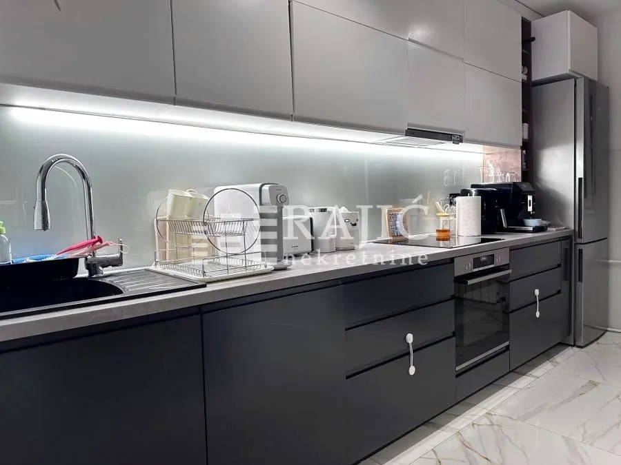 Modern kitchen with white and dark cabinets and built-in appliances.