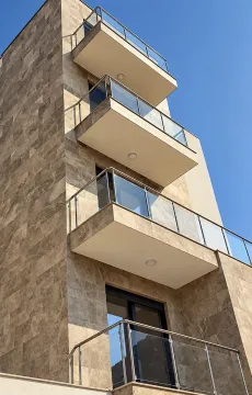 Pogled na spoljašnjost moderne stambene zgrade sa terasama i kamenom fasadom. - image 5