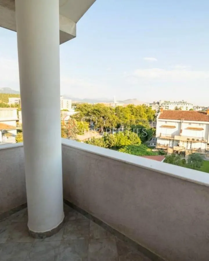Pogled sa balkona na okolne zgrade i zelenilo.
