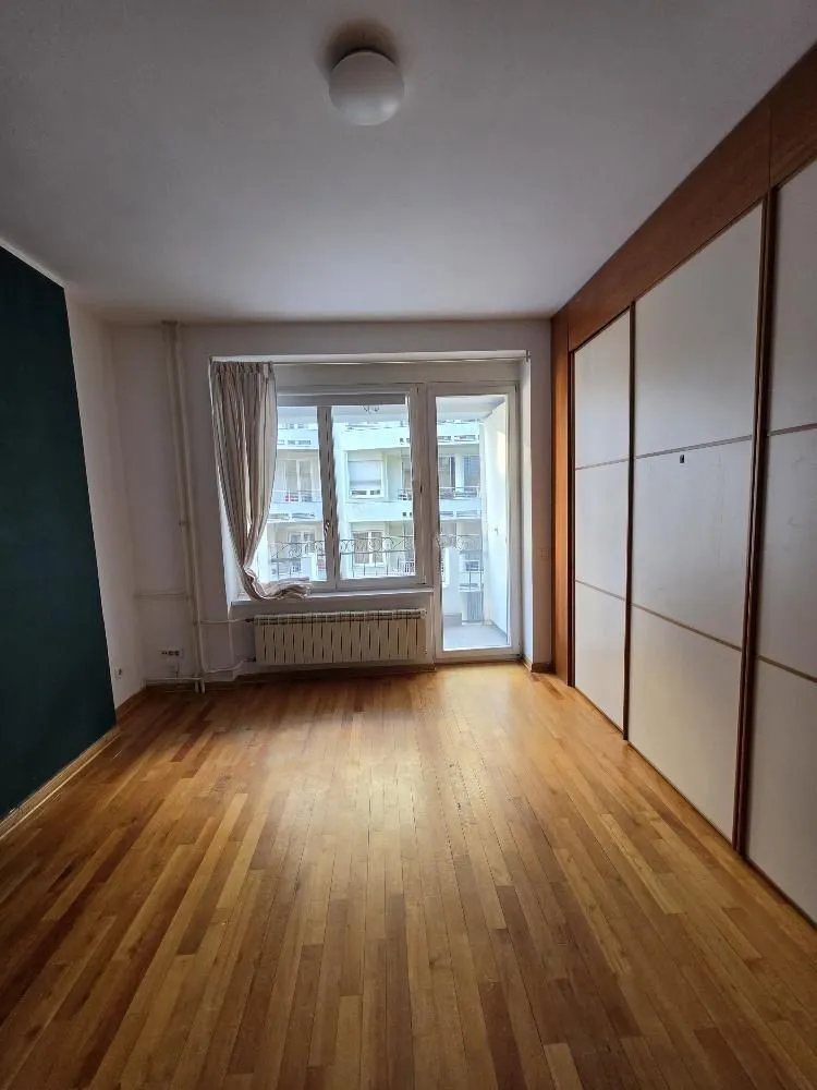 Empty room with hardwood flooring, large built-in wardrobe, and access to a balcony.