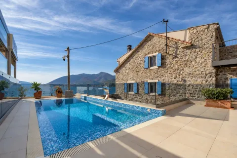 Terrace with a swimming pool and sea view in front of a stone house. - image 15