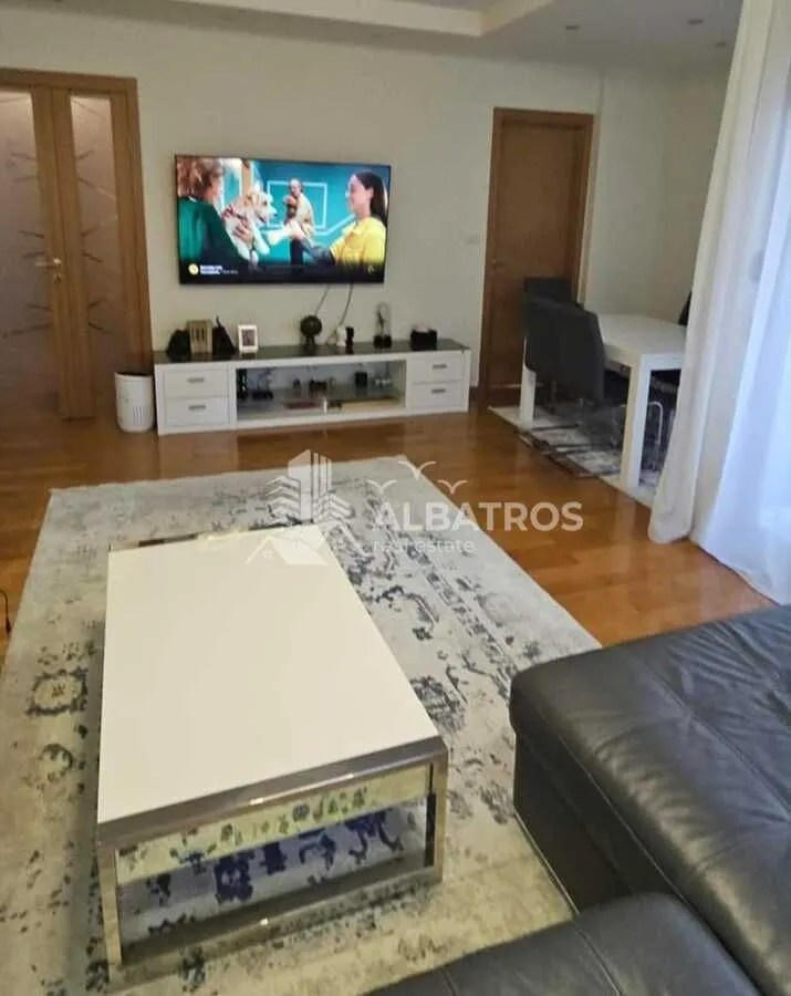 Dnevna soba sa garniturom, TV-om i trpezarijskim stolom.