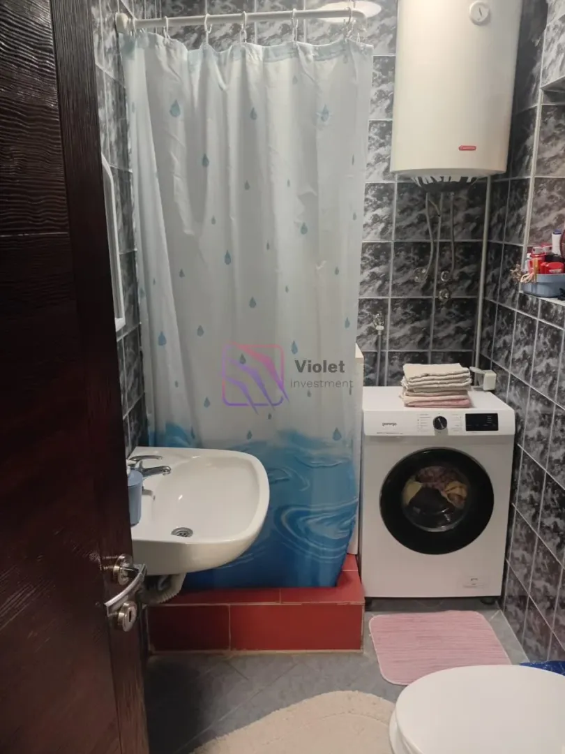 Small bathroom with a shower cabin, washbasin, and washing machine.