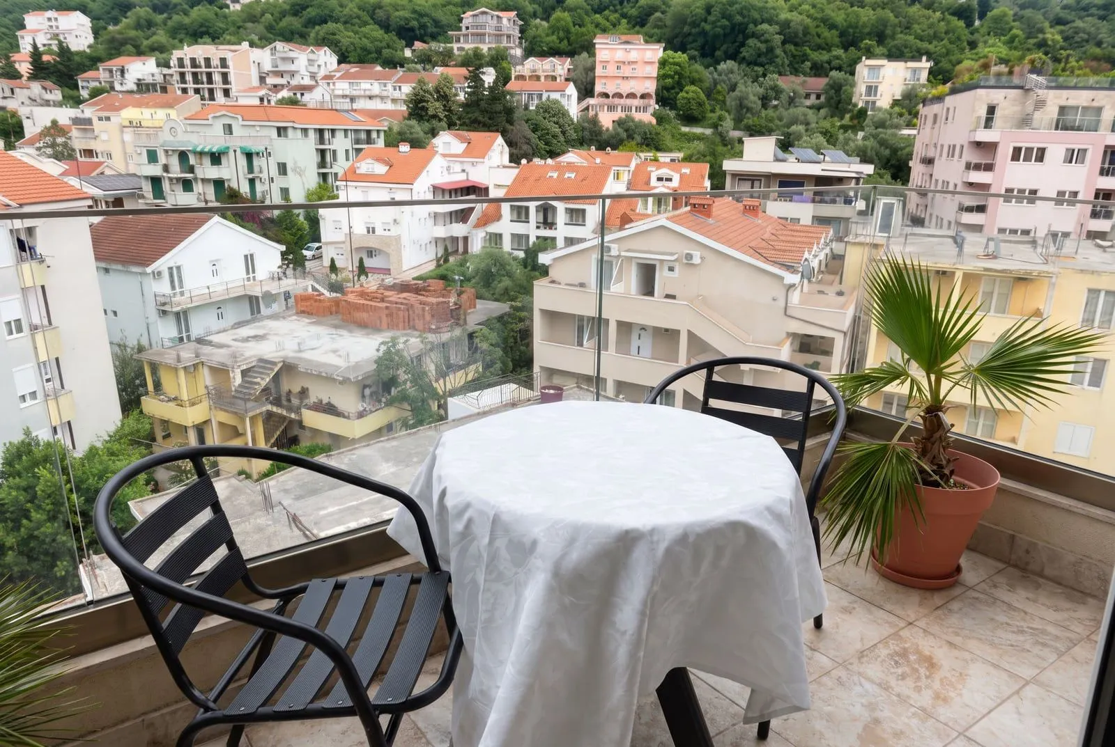 Namještena terasa sa stolom, stolicama i pogledom na naselje.