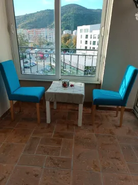 Covered terrace with two blue chairs and a small table with a city view. - image 2