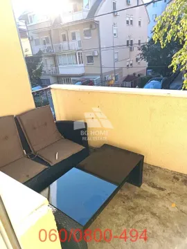 Small furnished balcony with seating furniture and a view of surrounding buildings. - image 13
