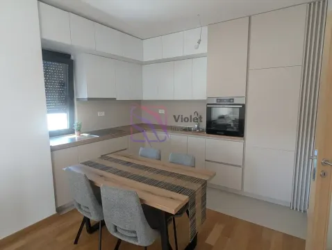 Modern kitchen with white cabinetry and a dining table with chairs. - image 10