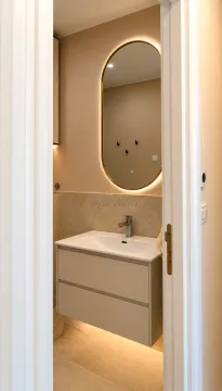 View through the doorway into a modern bathroom with a vanity and illuminated mirror. - image 10