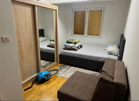 Small bedroom with a bed, wardrobe, and piled blankets. - image 4