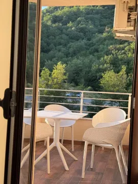Furnished balcony with a table, chairs, and a view of greenery. - image 4