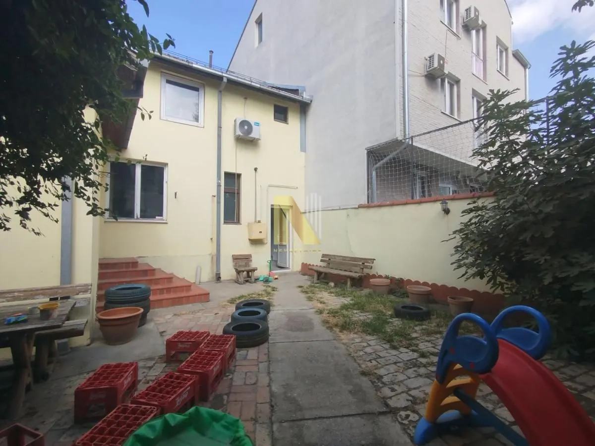 Family house yard with a paved area and greenery.