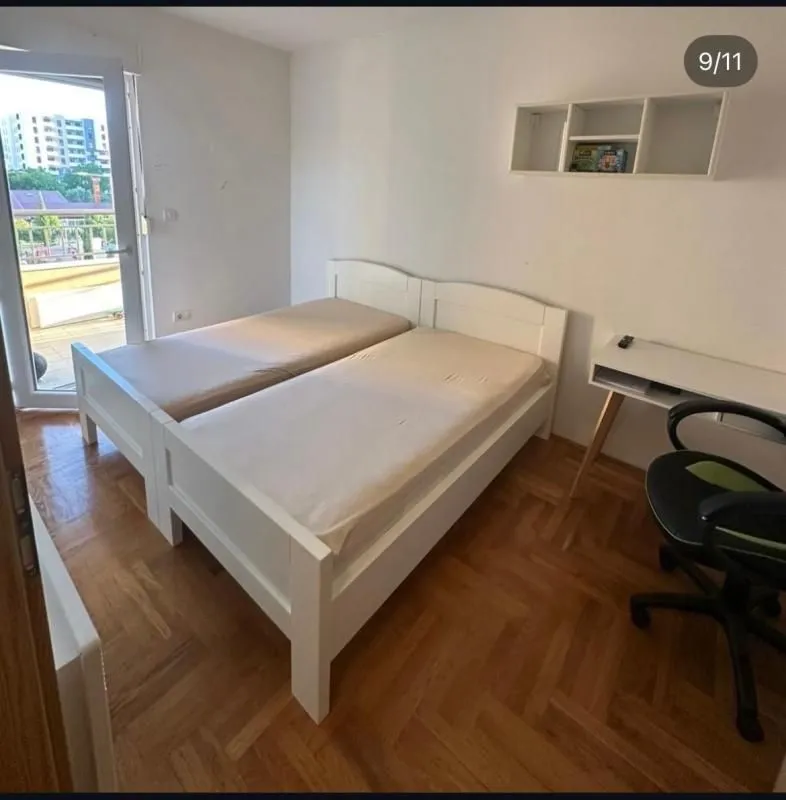 Spavaća soba sa dva kreveta i radnim stolom.