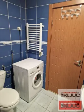 Kupatilo obloženo pločicama sa veš mašinom i vratima. - image 10