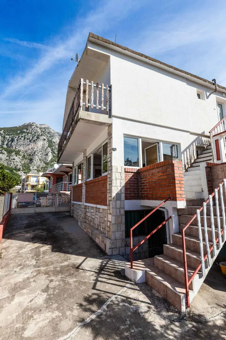 Eksterijer kuće sa spoljnim stepeništem i dvorištem.