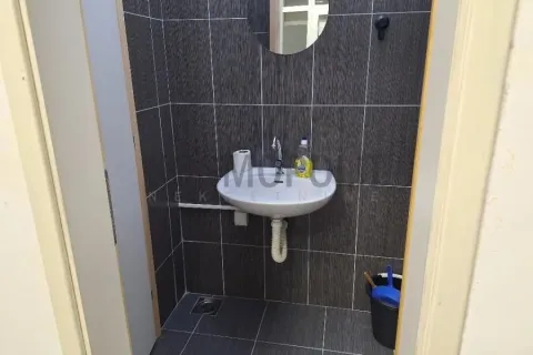 Smaller bathroom lined with dark tiles featuring a washbasin and a mirror. - image 8