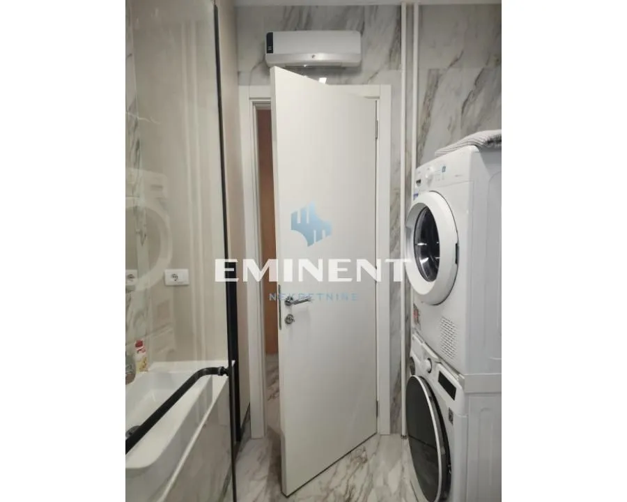 Bathroom with a walk-in shower, washbasin, and stacked washing machine and tumble dryer.