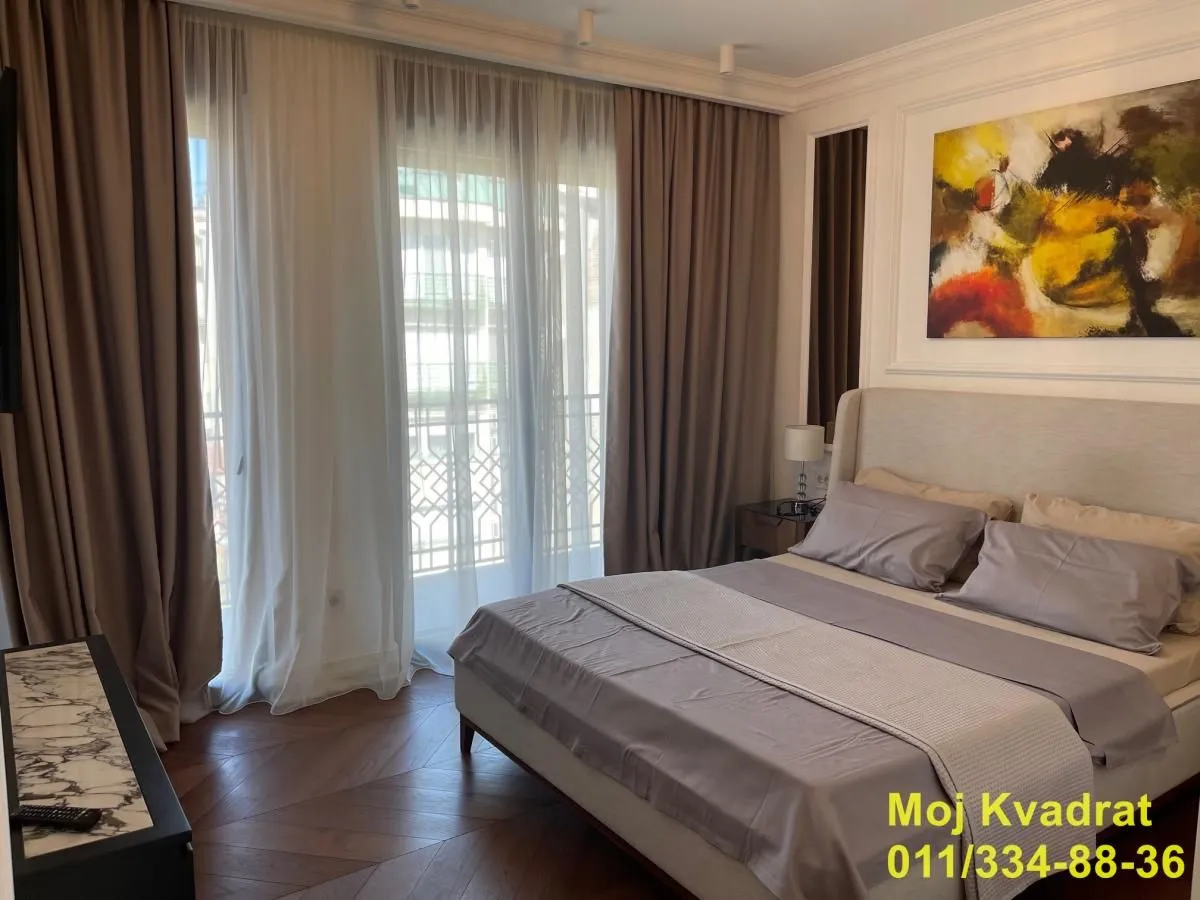 Modern bedroom with a double bed, artwork, and balcony doors with curtains.