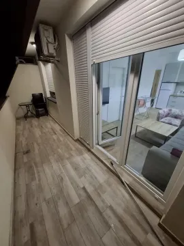 Long covered terrace with wooden flooring and a view of the apartment interior through glass doors. - image 16