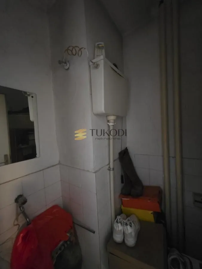 Pogled na starije kupatilo sa sanitarijama i pločicama.