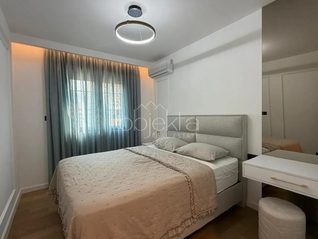 Furnished bedroom with a double bed, curtains, and built-in lighting.