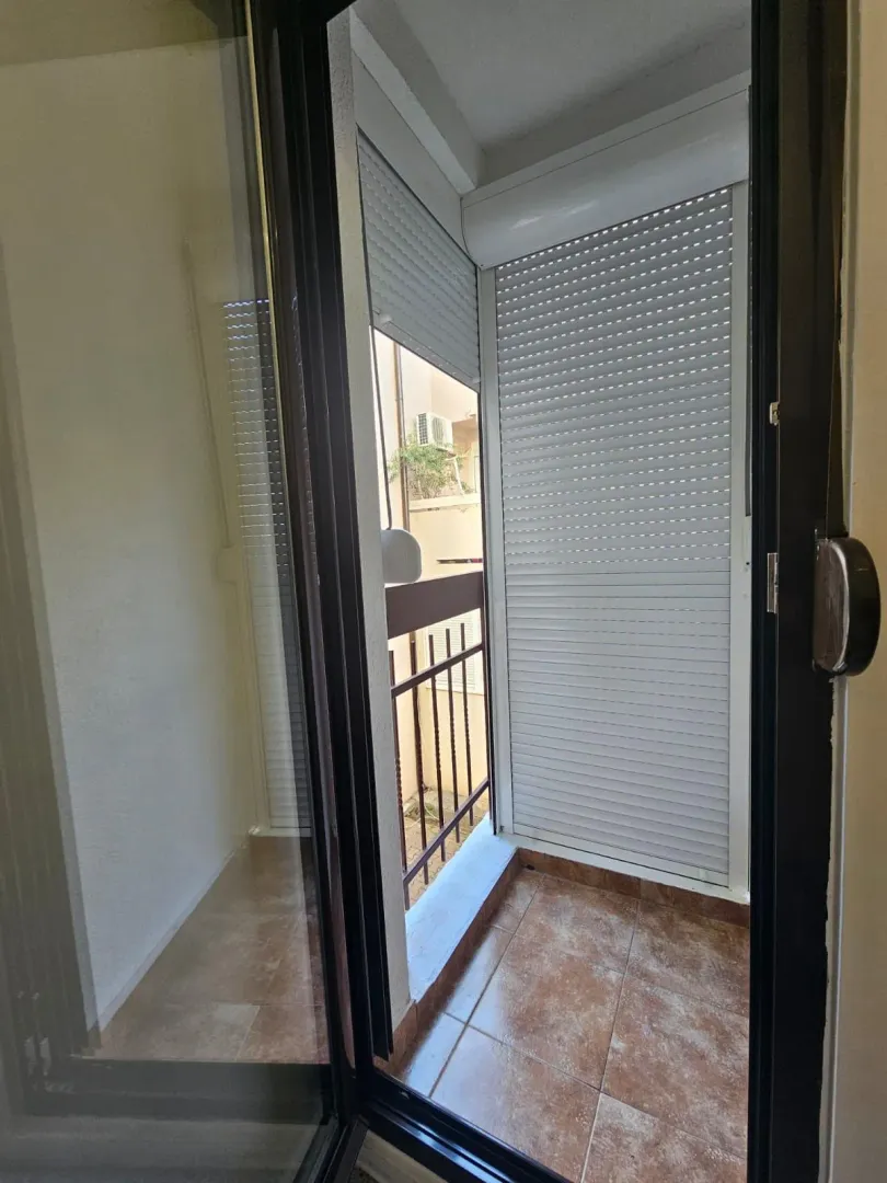Manji popločani balkon sa spuštenim roletnama.