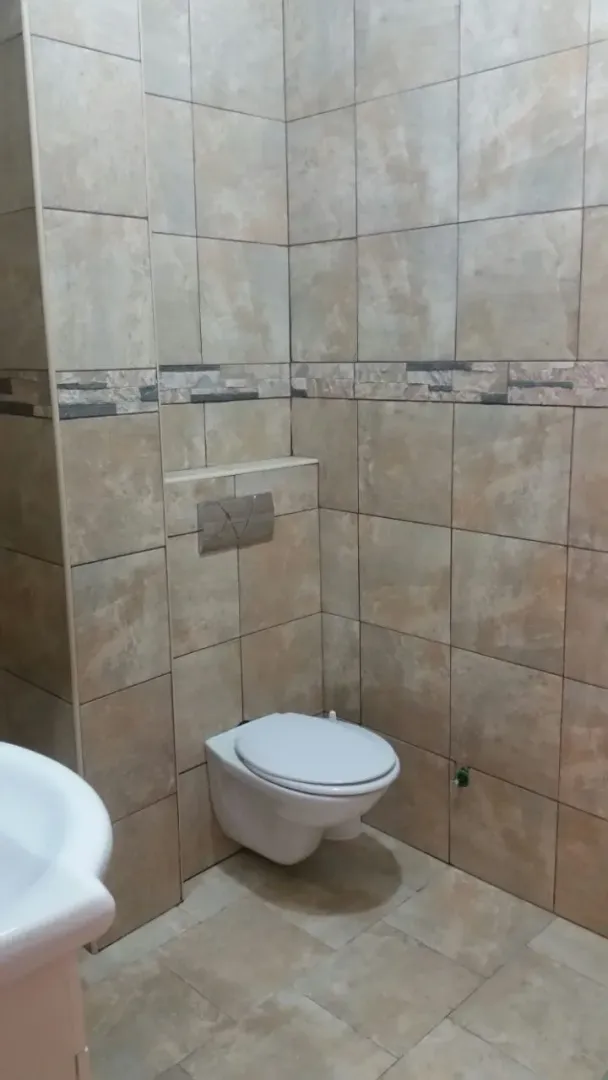 Bathroom featuring a wall-mounted toilet and beige tiles.
