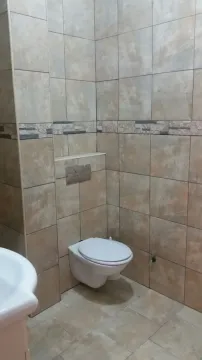 Bathroom featuring a wall-mounted toilet and beige tiles. - image 6