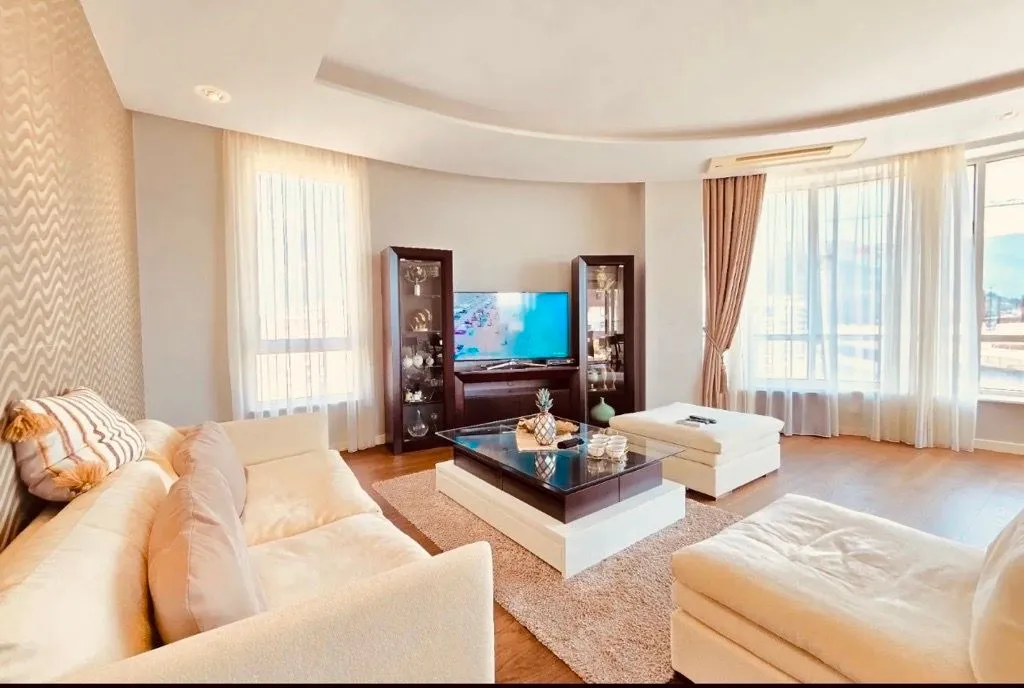Spacious and bright living room with seating furniture and TV unit.