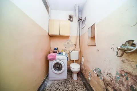 Starije kupatilo sa toaletom i veš mašinom kojem je potrebna renovacija. - image 9